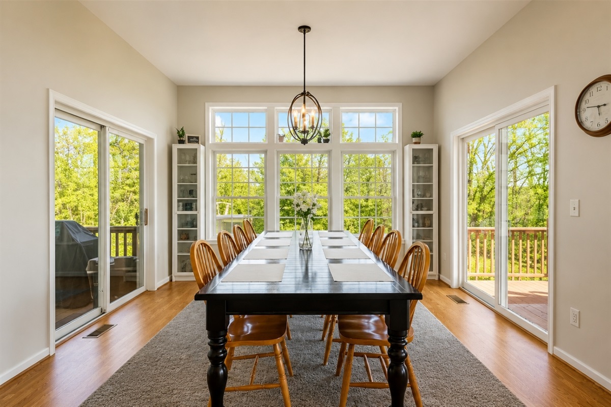 Dine in style with nature as your backdrop in this bright, spacious dining room, featuring floor-to-ceiling windows and elegant furnishings.
