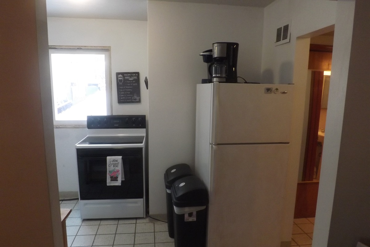 Full kitchen with refrigerator, stove, microwave, coffee makers, and most essentials
