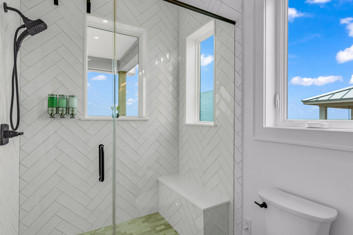 Cair Paravel: A herringbone-tiled walk-in shower with a built-in bench and corner window makes this ensuite feel like a private retreat.