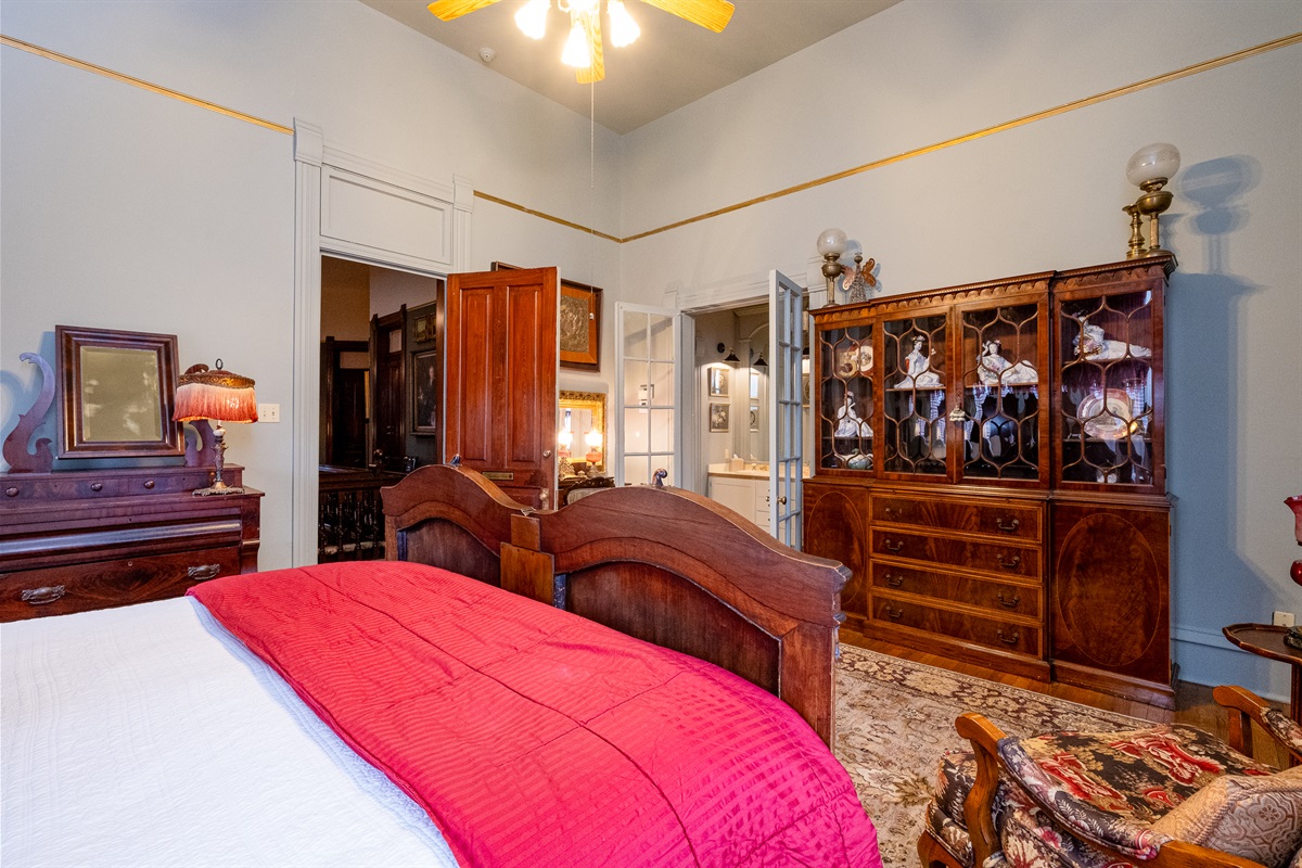 Bedroom view showcasing the carved wood bed, period cabinetry, and rich textiles.