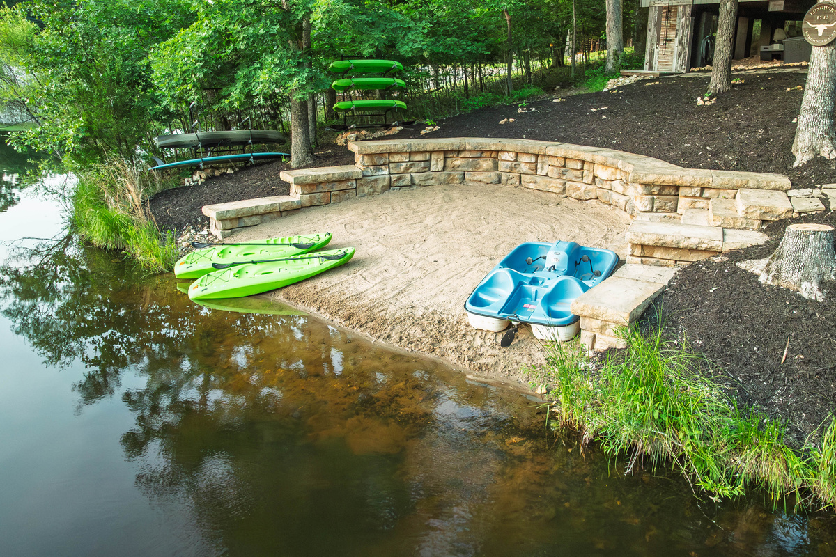 Sandy beach with kayaks and paddle boat included for guests.