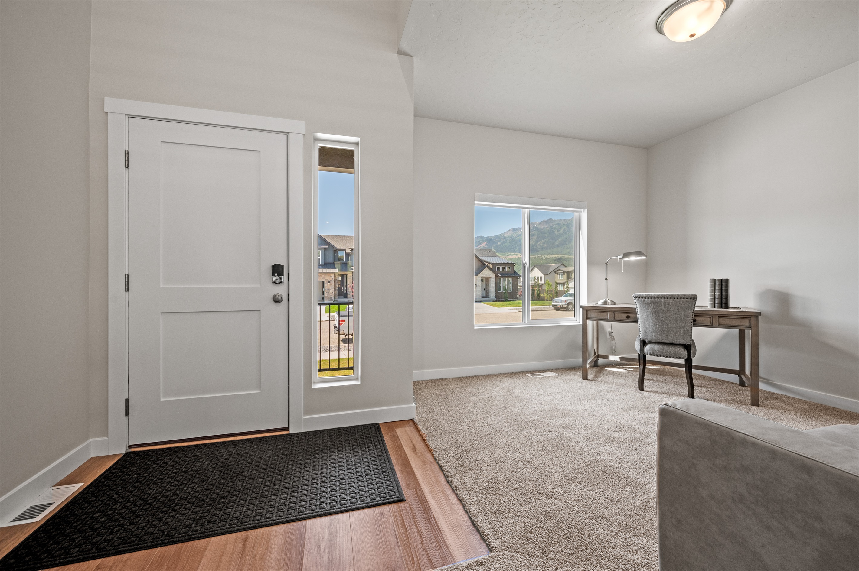 Bright office space off the foyer with sofa, desk, and large window.