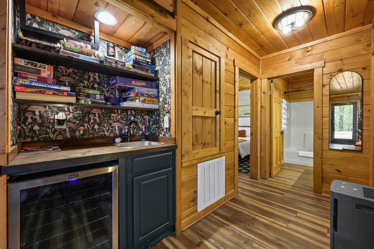 Wet bar with a beverage fridge downstairs and shelves stocked with games