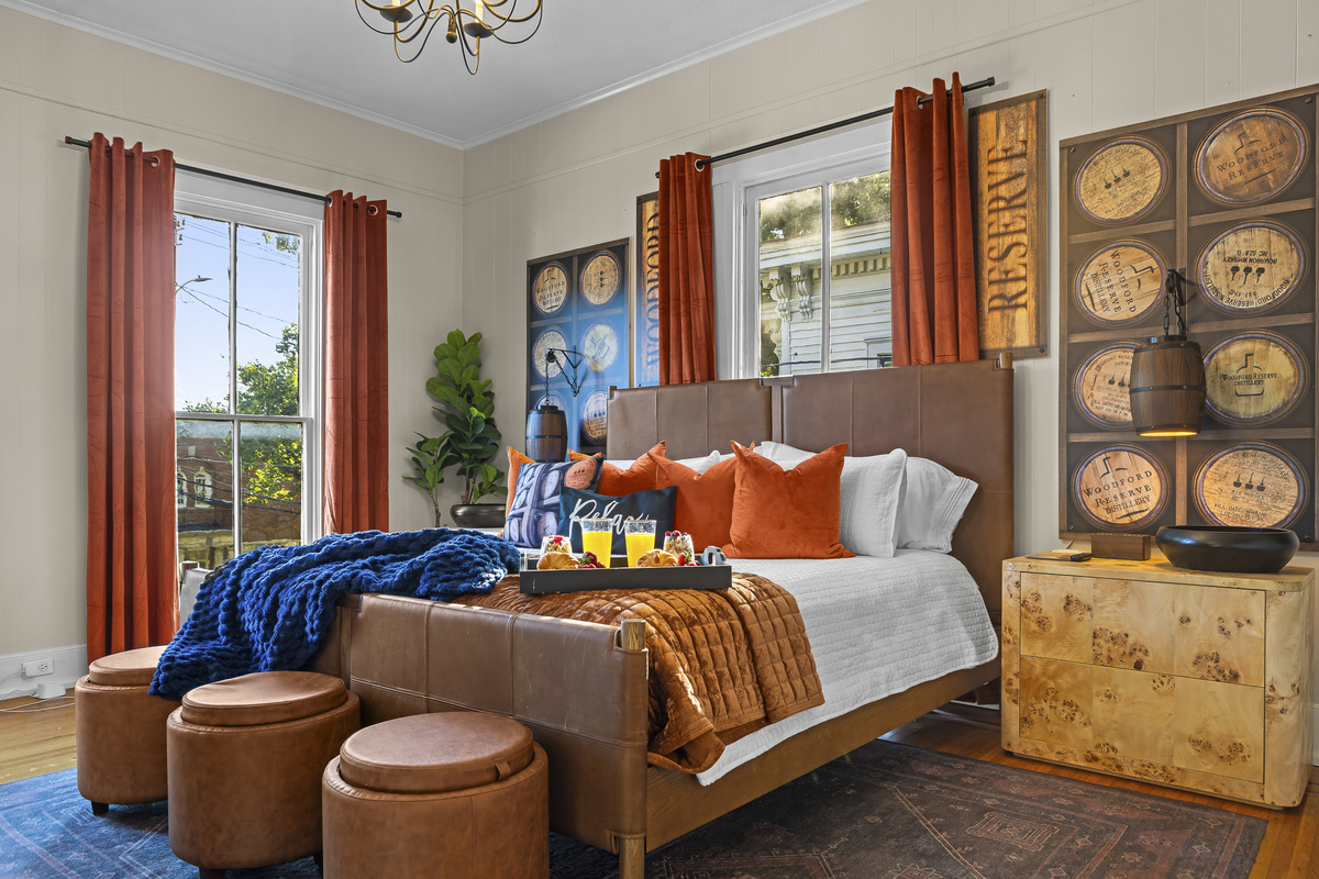 Wake up in the Woodford Reserve Room, featuring a king bed, bourbon barrel art panels, burnt-orange drapes, and a TV with Netflix above the fireplace.