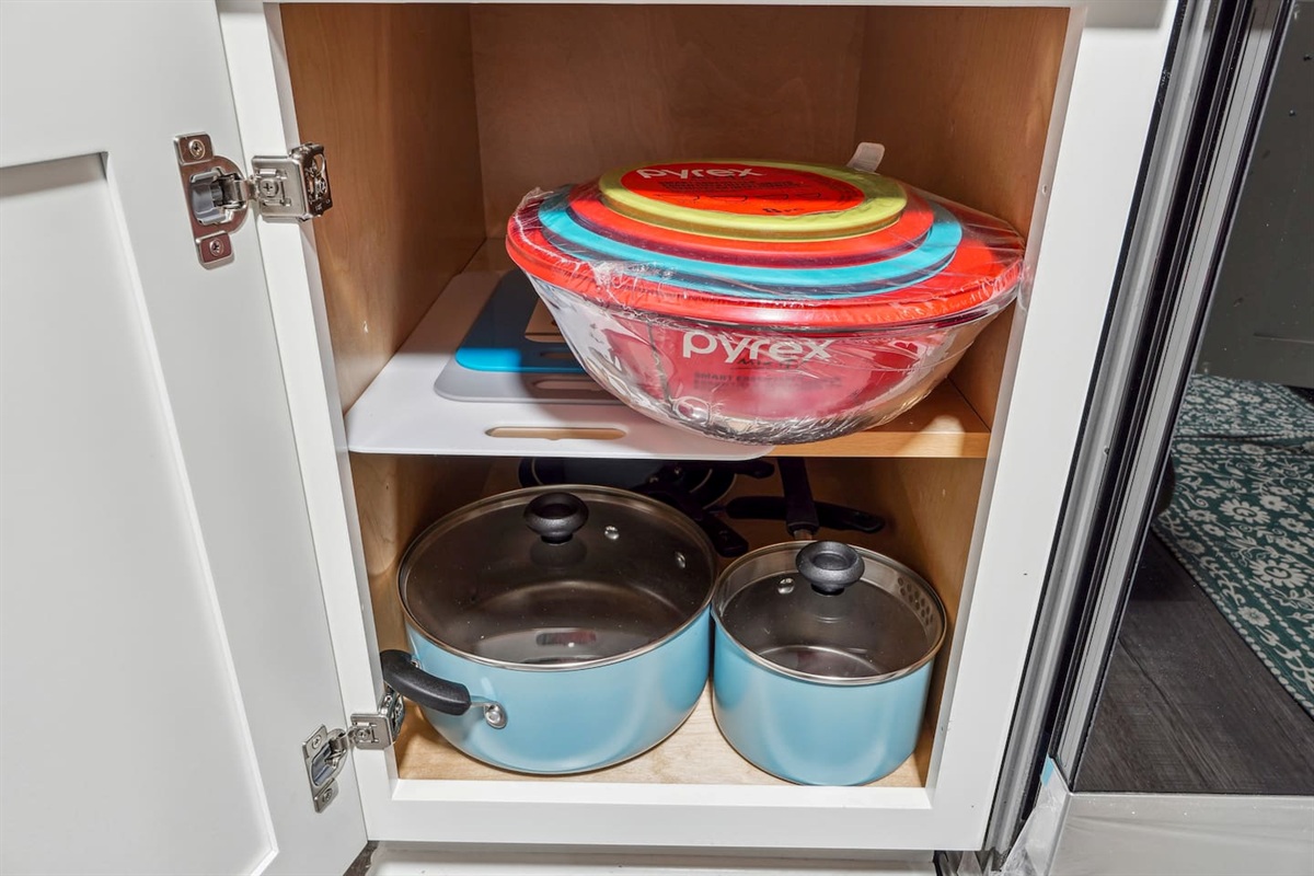 A fully equipped kitchen with a refrigerator, microwave, stove, oven,fridge, dishwasher, coffee maker, kettle, toaster, and blender. Includes plates, bowls, utensils, pots, and pans, plus four bar chairs for casual dining or socializing.
