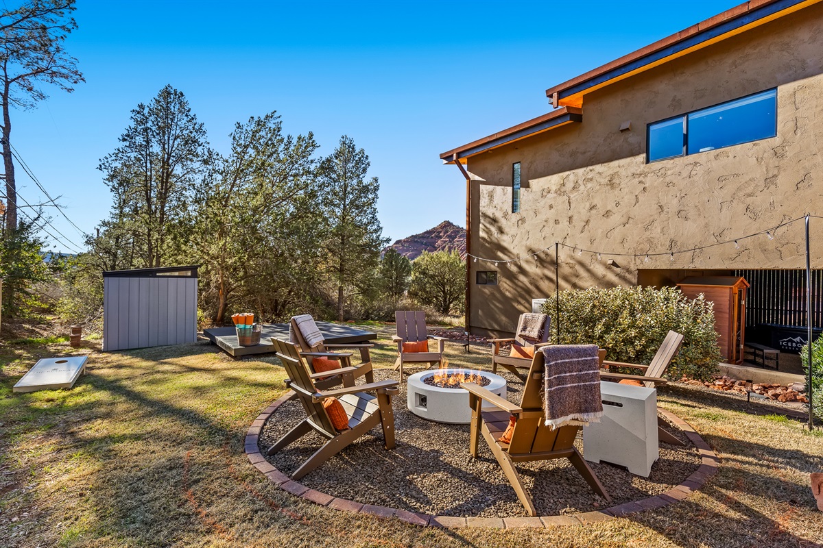 A spacious backyard featuring a central fire pit, comfortable seating, and a dedicated yoga platform - set against Sedona’s desert landscape for relaxation, movement, and connection.