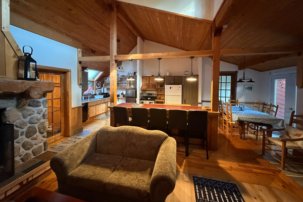 In front of fireplace with kitchen and dining area at other end of room