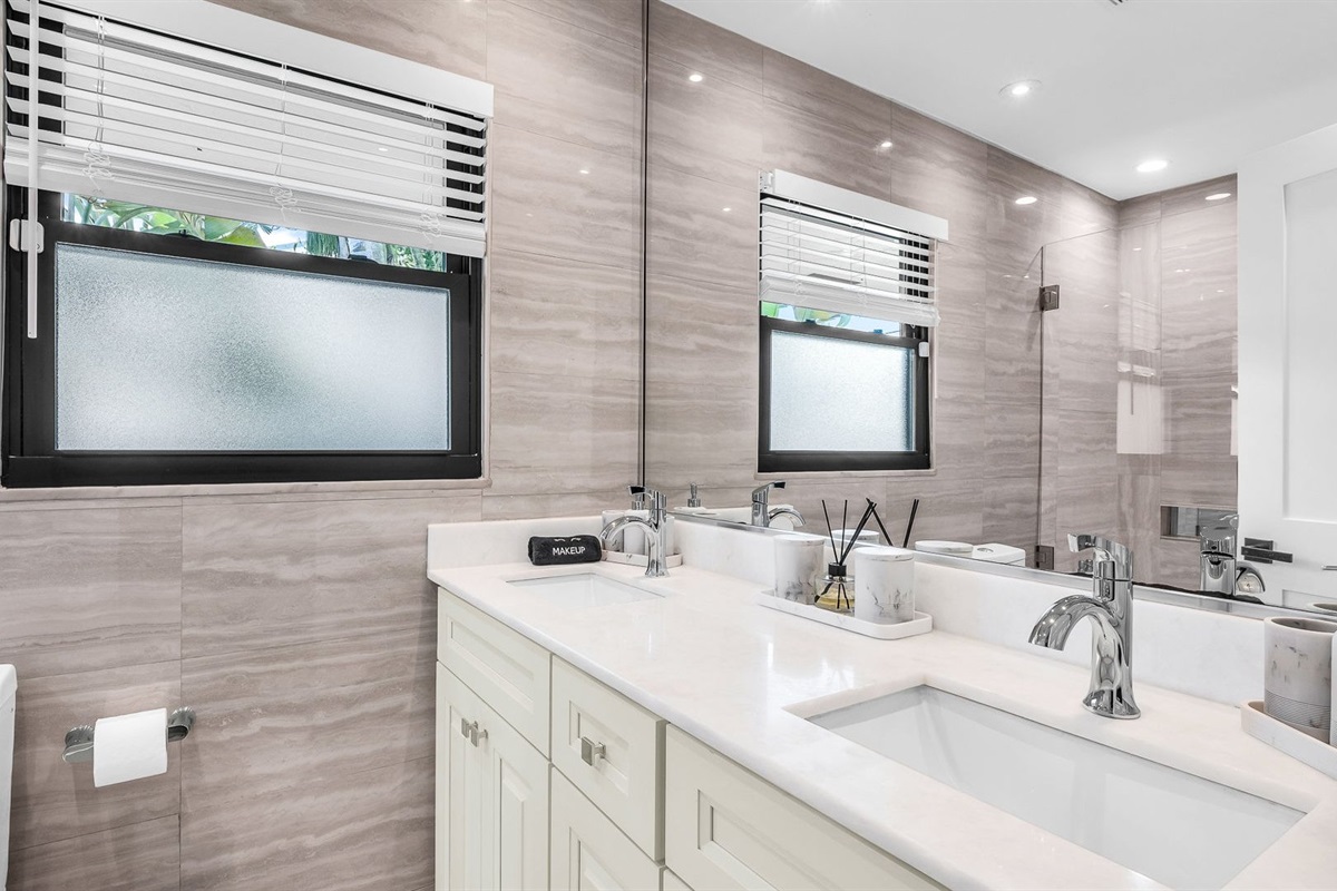 The ensuite bathroom features a sleek double vanity, elegant stone finishes, and a spa-like shower/tub combo with glass enclosure. Designed for both style and comfort, it’s the perfect space to refresh and unwind