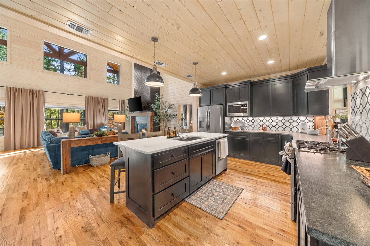 Spacious kitchen hub with island seating, black cabinetry, and effortless access to both the dining area and outdoor living spaces.