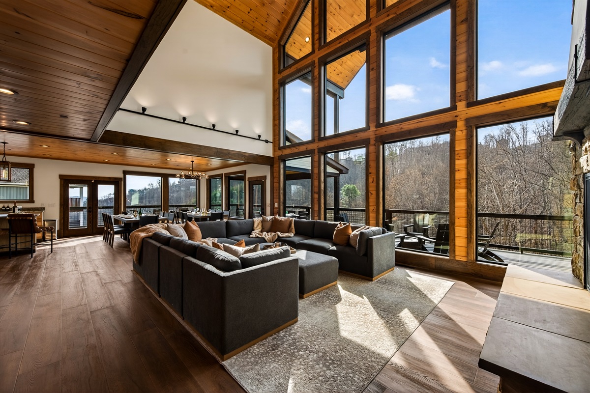 Gather beneath 30-foot vaulted ceilings surrounded by a wall of windows. Relax on the large sectional sofa beside the luxury fireplace with stunning floor-to-ceiling stone, creating a warm and unforgettable mountain lodge atmosphere.