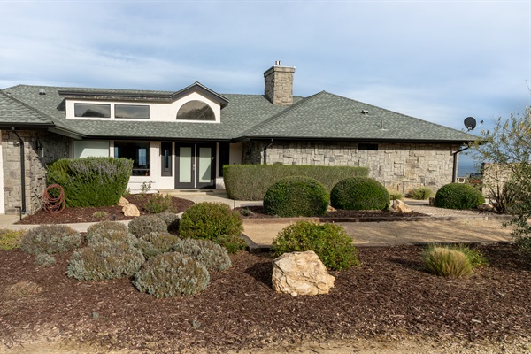 Welcome to the hilltop. The stone-clad exterior, manicured grounds, and classic arched window hint at everything waiting inside — and the valley views peeking out on the right tell the rest of the story.