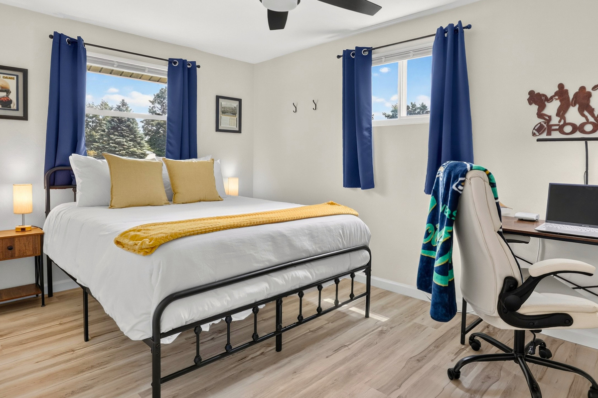 Queen bedroom with a dedicated workspace, ergonomic executive chair, and subtle Notre Dame touches.