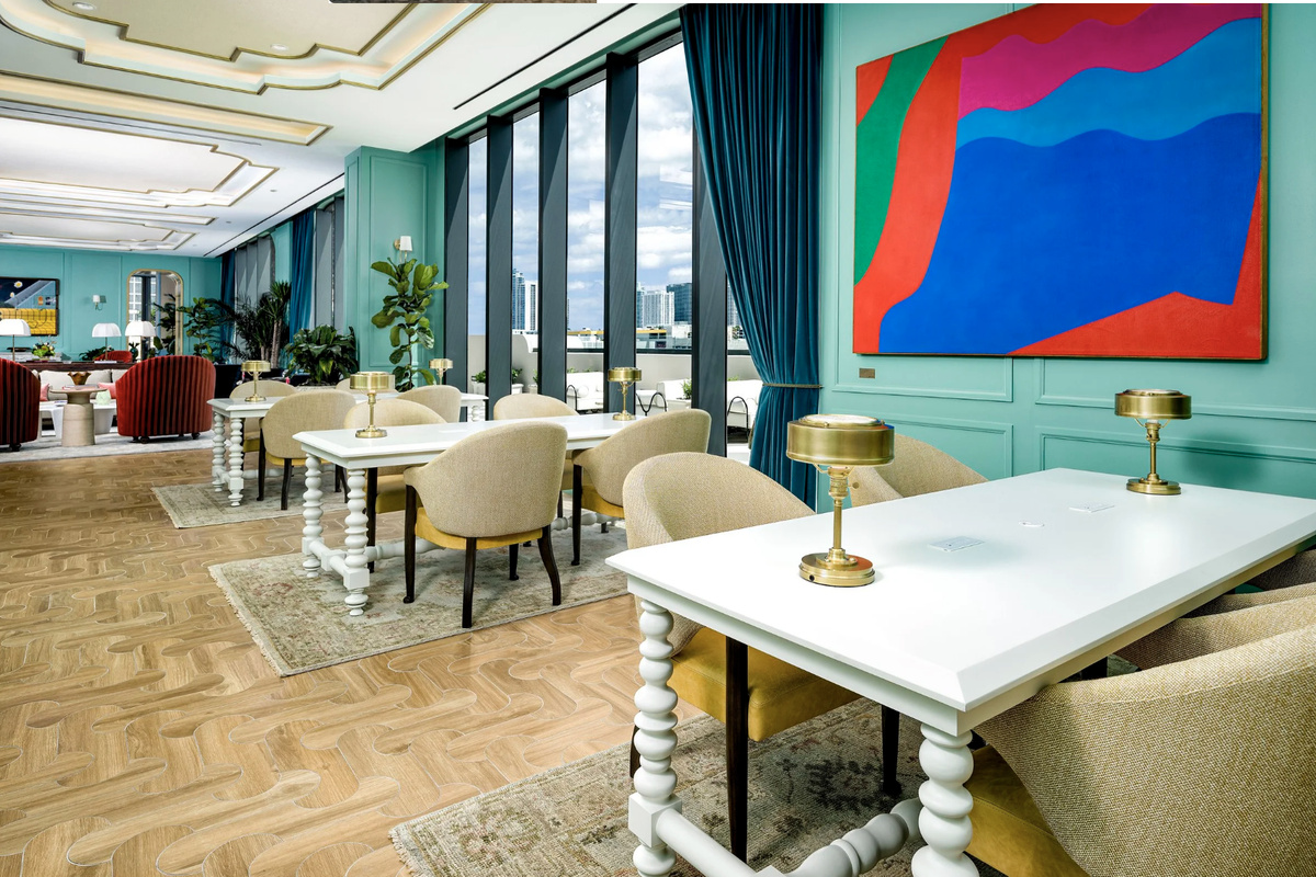 A light-filled clubroom where marble cafe tables and designer seating open to the terrace beyond.