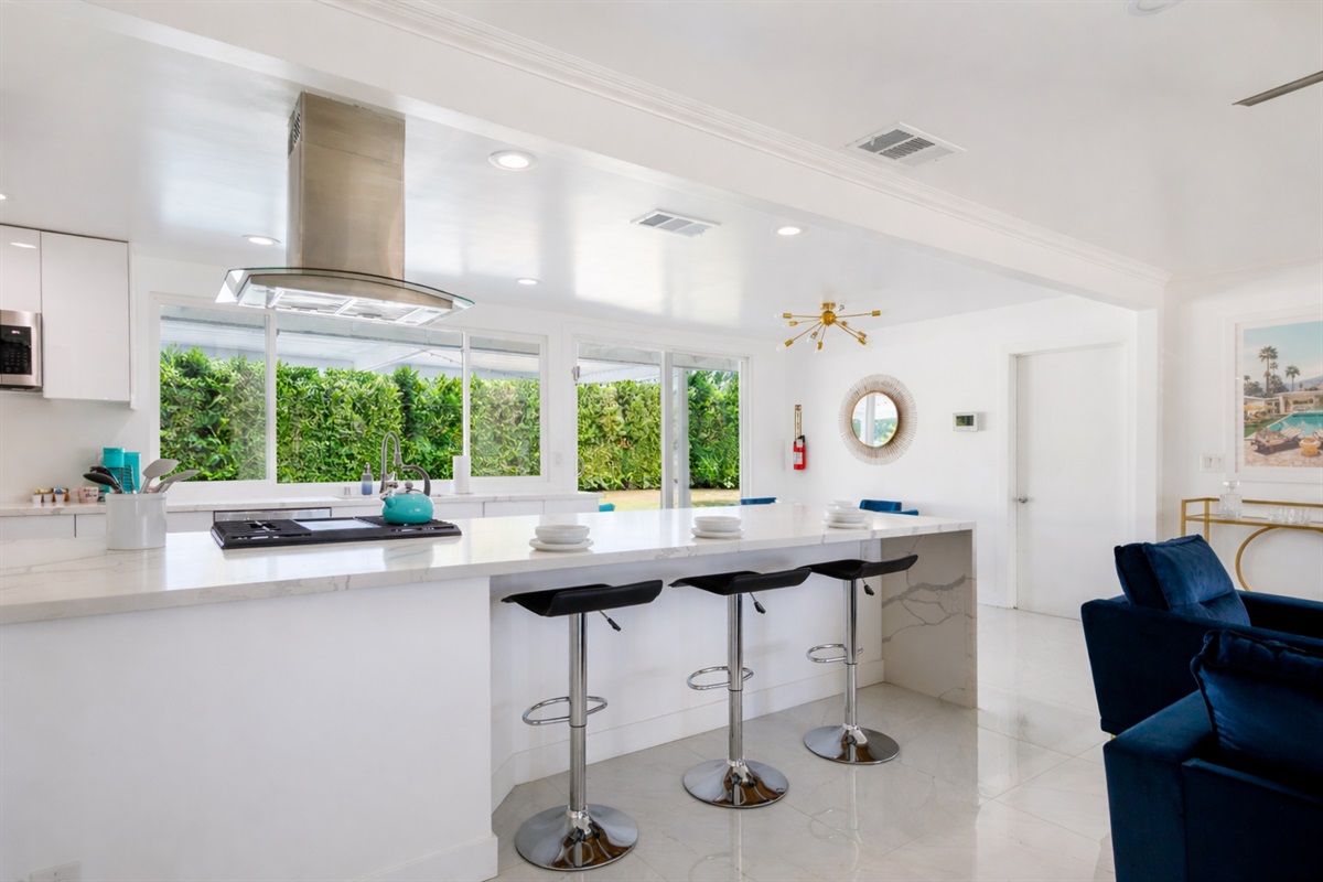 Enjoy a meal at the sleek, modern counter, where the natural light streaming through the windows highlights the beauty of the spacious kitchen.
