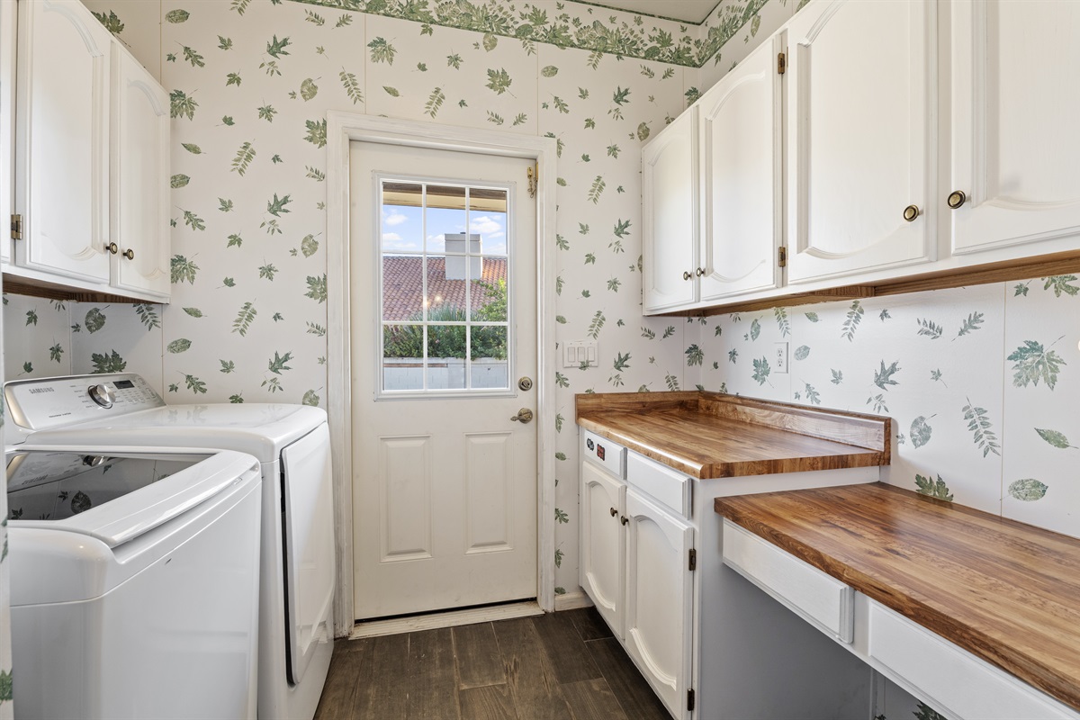 Fresh and functional, the laundry room pairs charming wallpaper with updated appliances and access to the outdoors.