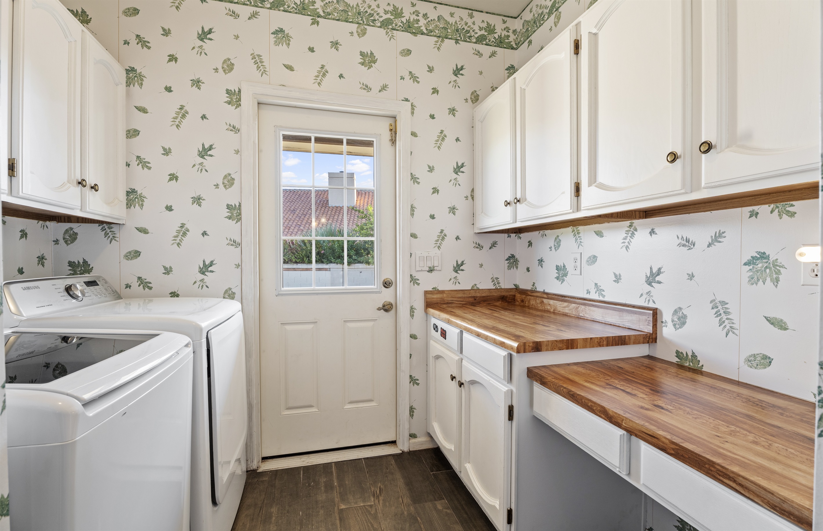 Fresh and functional, the laundry room pairs charming wallpaper with updated appliances and access to the outdoors.