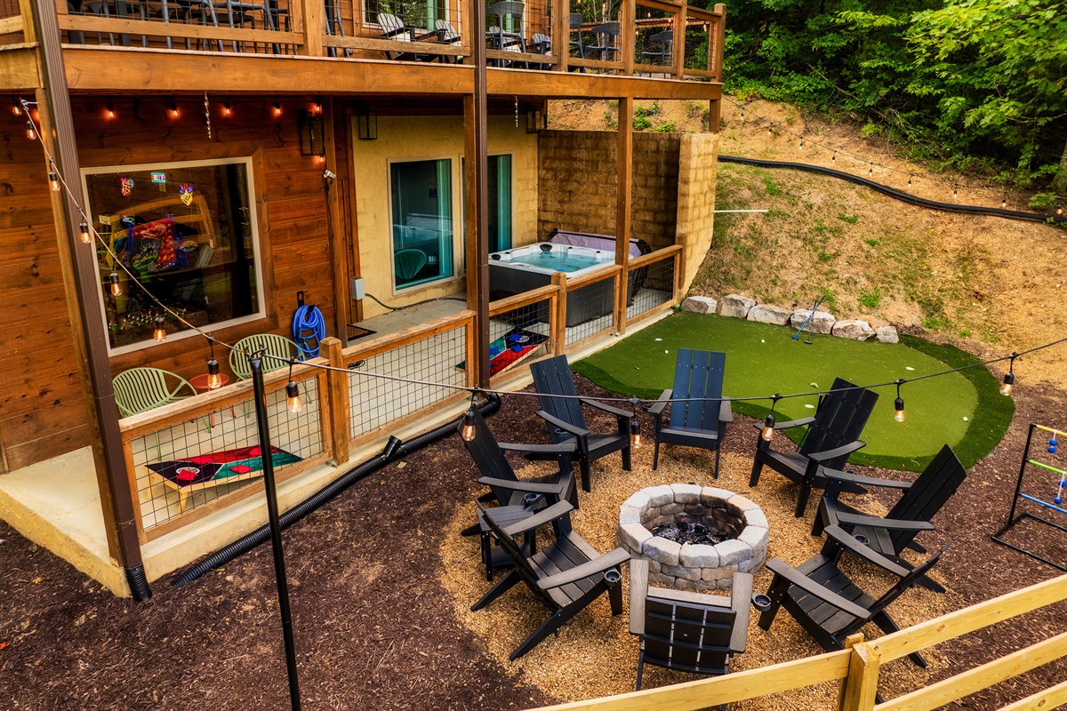 Luxury cabin with multiple decks with string lights, hot tub, and backyard with fire pit, mini golf, and outdoor games