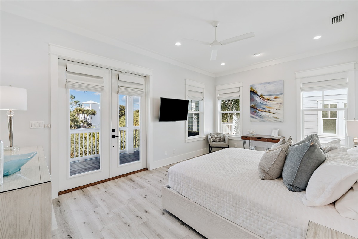 Second-floor master en suite featuring a king bed, smart TV, writing desk, large walk-in closet, and private screened-in balcony.