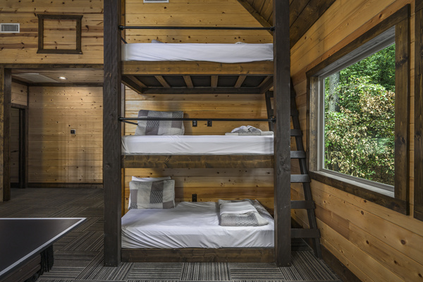 Cozy triple bunk beds with rustic wood finishes and beautiful forest views—perfect for kids and teens.
