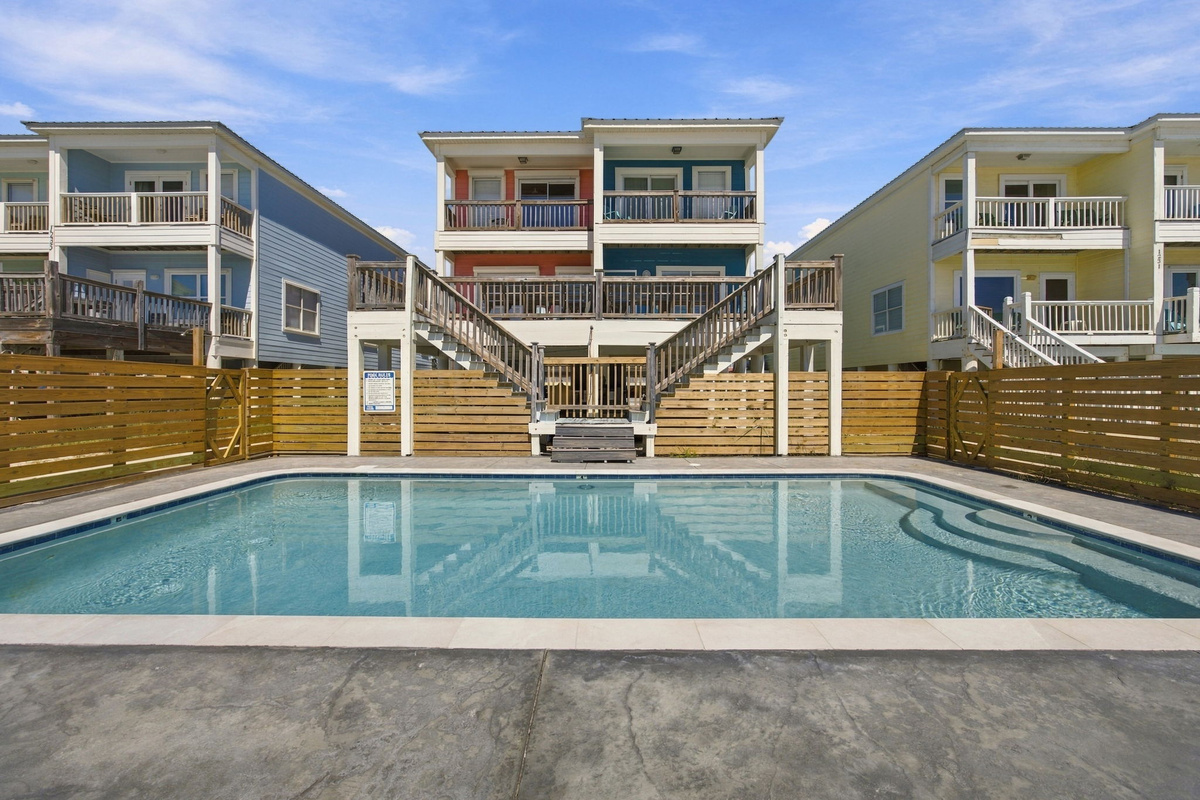 Inviting swimming pool surrounded by a spacious deck and outdoor lounge area at this coastal vacation rental.
