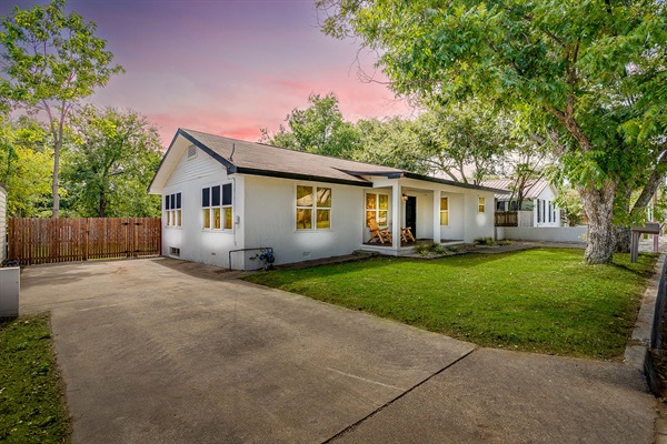 Front of the home with charming curb appeal, shade trees, and large driveway