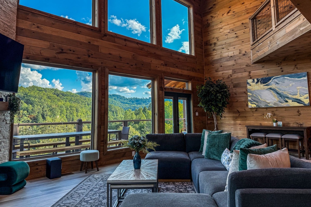 Soaring ceilings, warm wood walls, and wall to wall windows frame sweeping mountain views in this inviting great room. Cozy seating, natural light, and peaceful scenery set the tone for slow mornings and fireside evenings.