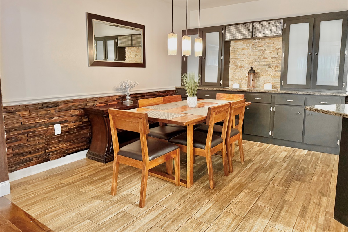 Enjoy cozy meals or family game nights around this modern wooden dining table, set under warm pendant lighting and open to both the kitchen and living room.