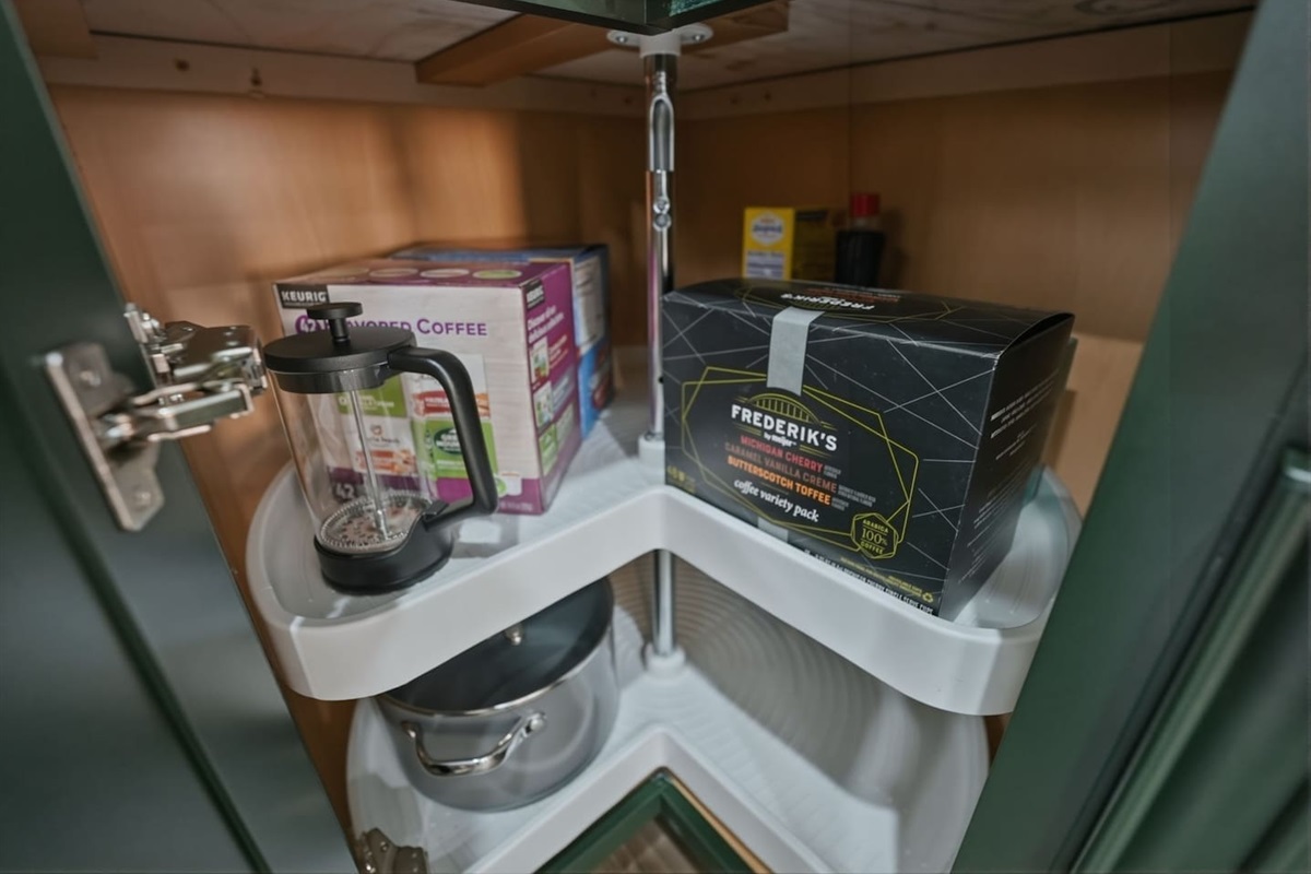 Organized kitchen storage with cookware, French press coffee maker, and coffee variety packs to suit every taste.