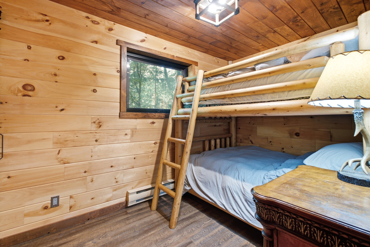 Bunk room with natural wood walls and comfortable bedding