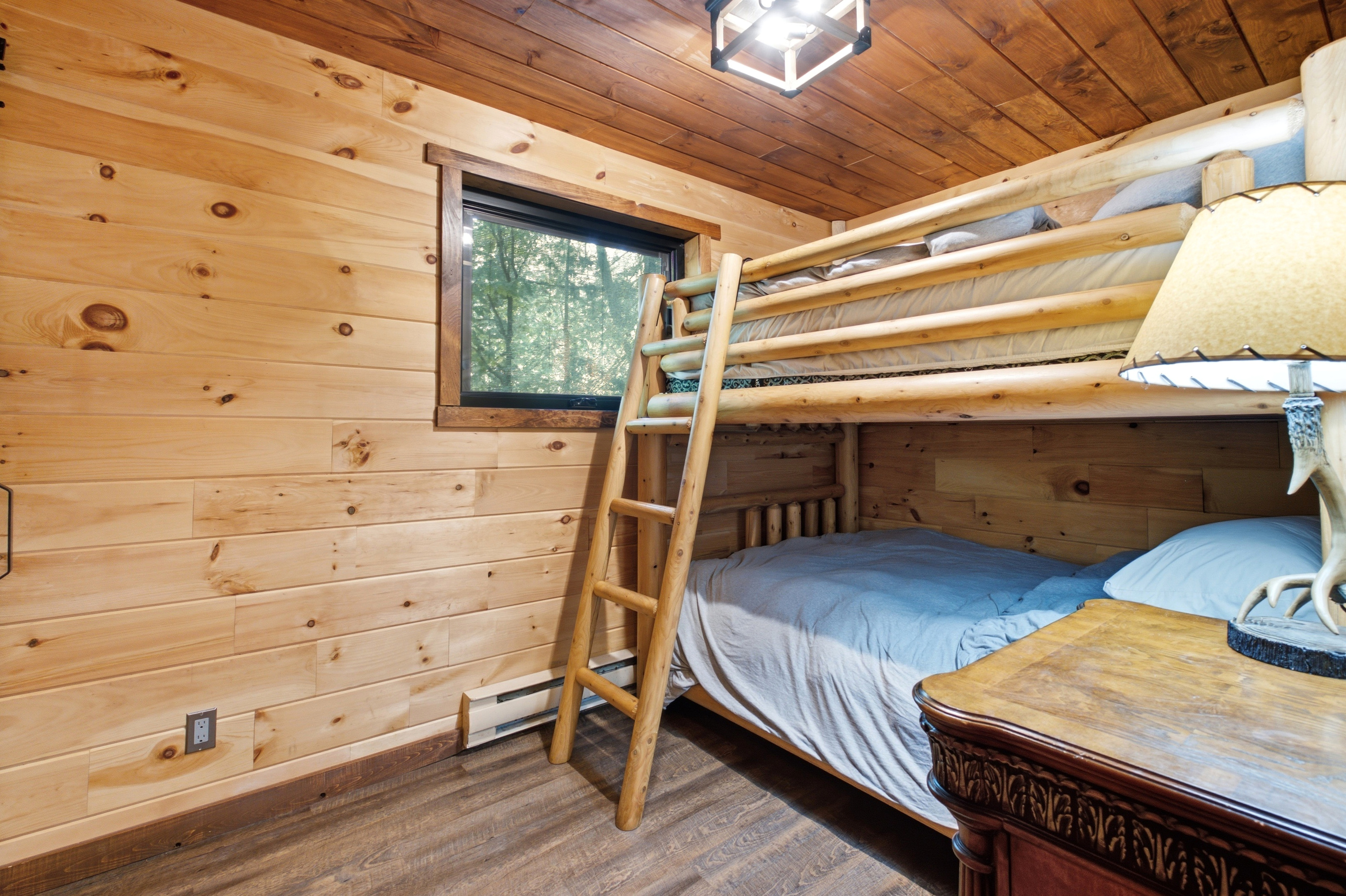 Bunk room with natural wood walls and comfortable bedding
