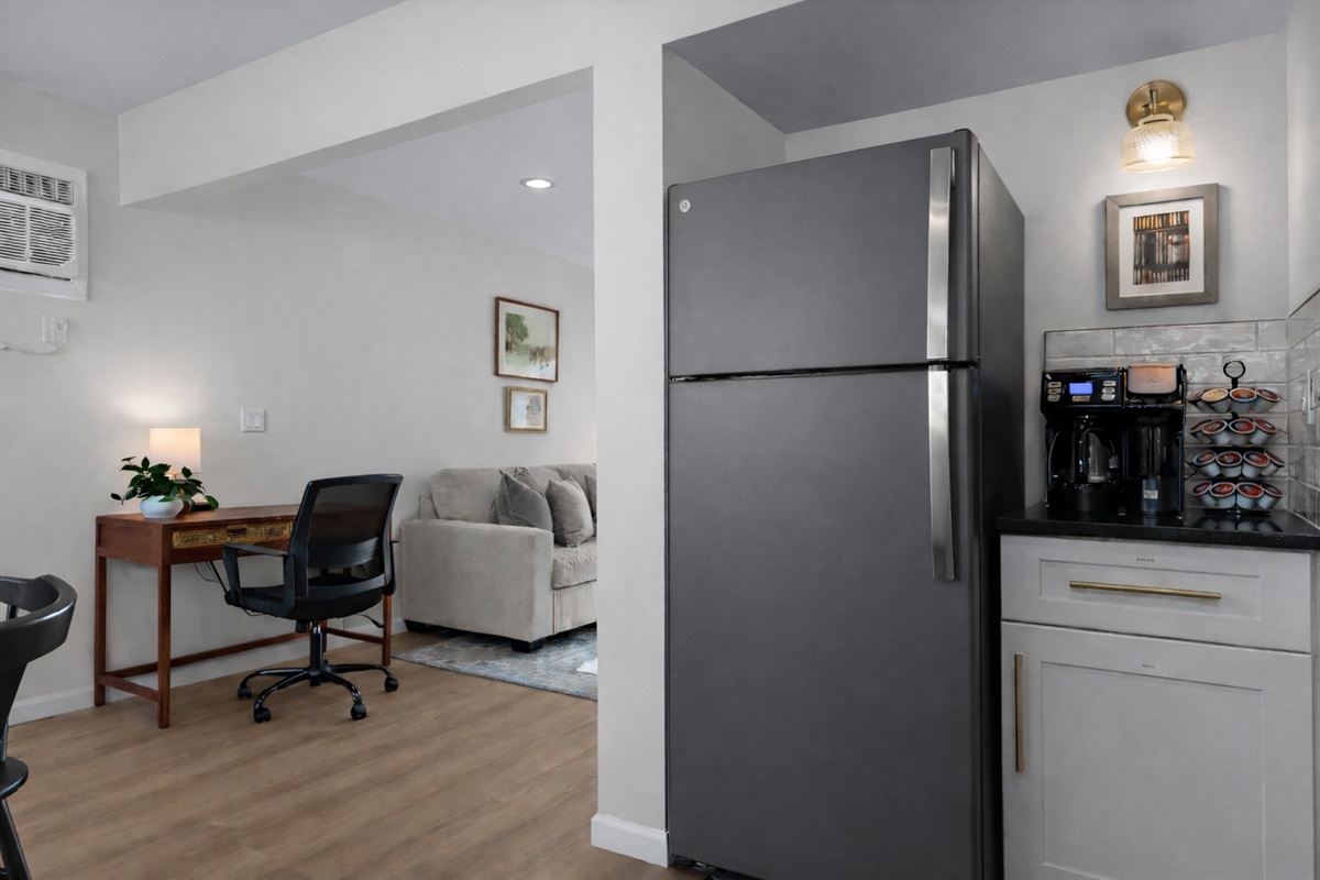 Thoughtfully designed kitchen corner with coffee station and modern appliances, flowing seamlessly into the living area and dedicated workspace.
