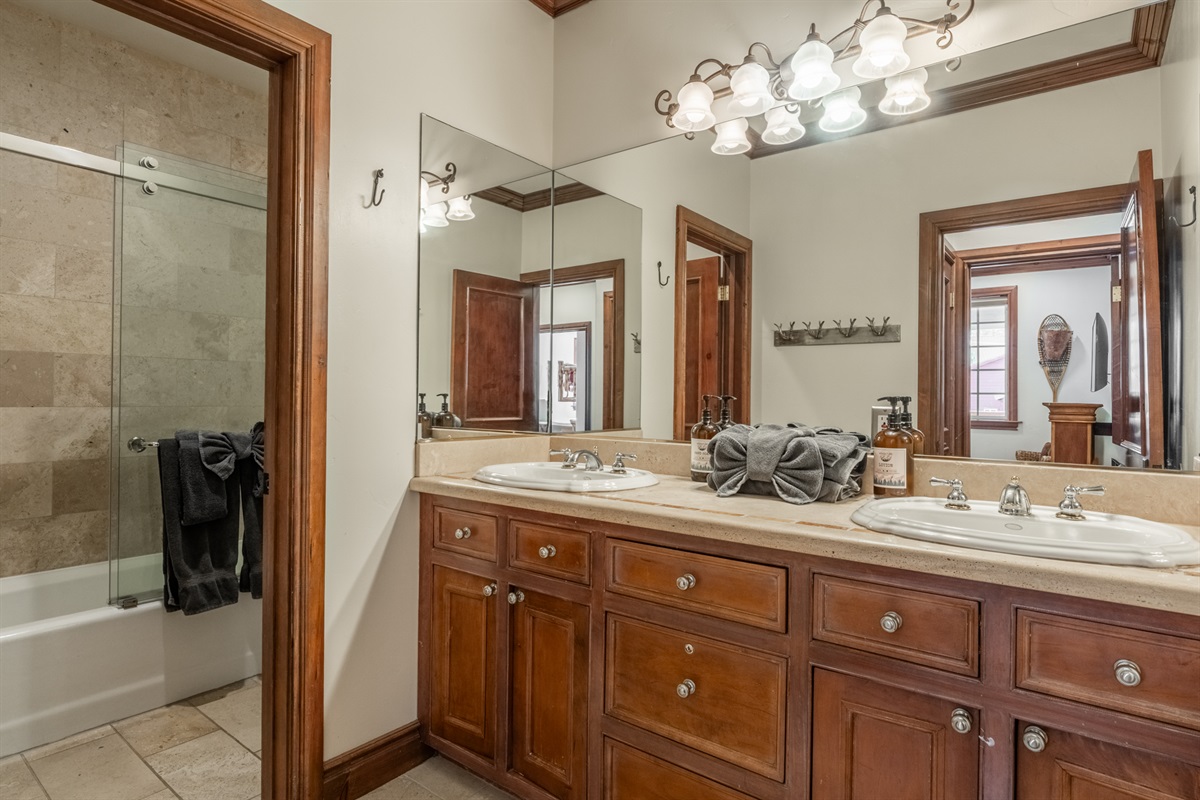 The The Refined Retreat guest bathroom features a shower/tub combination and a spacious vanity area just outside the bath, allowing multiple guests to get ready comfortably.