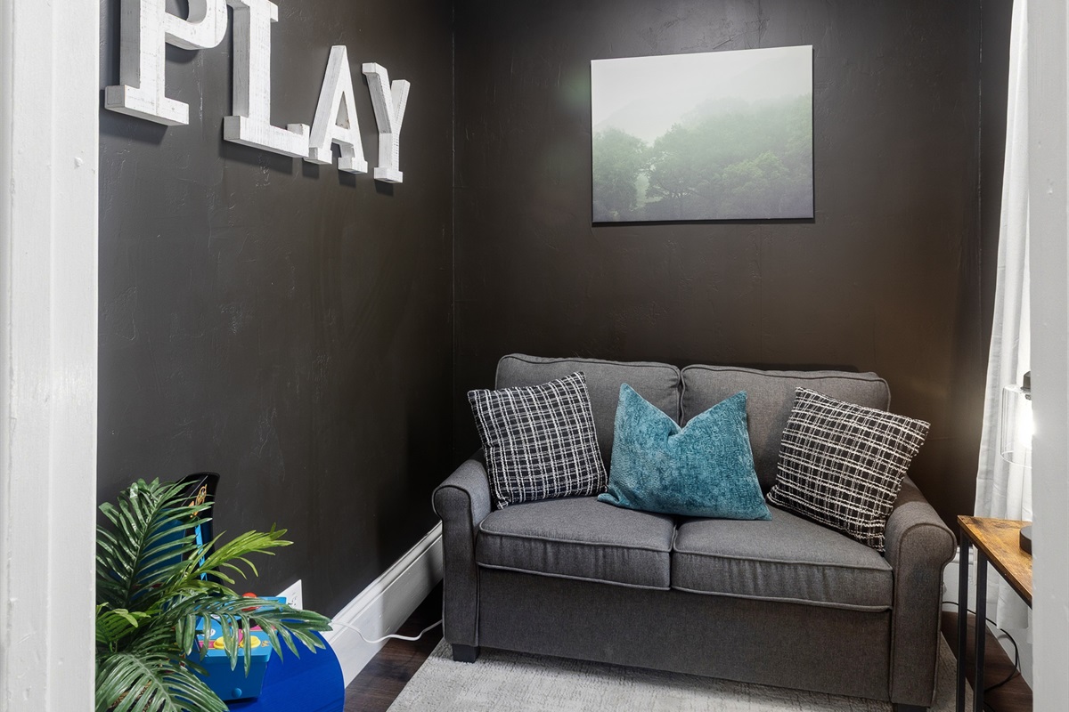 The play room doubles as a cozy lounge with a comfy loveseat and retro gaming