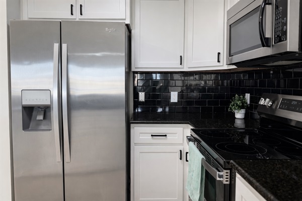 Stainless steel refrigerator, electric range, microwave, and granite countertops