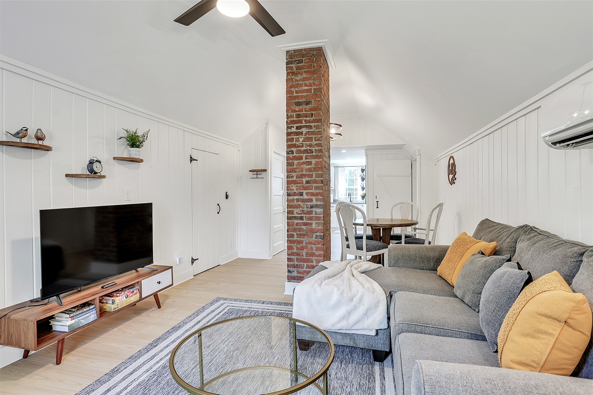 Settle into the warm, inviting living room—tall ceilings, soft light, and a comfy sofa make it the perfect place to unwind.