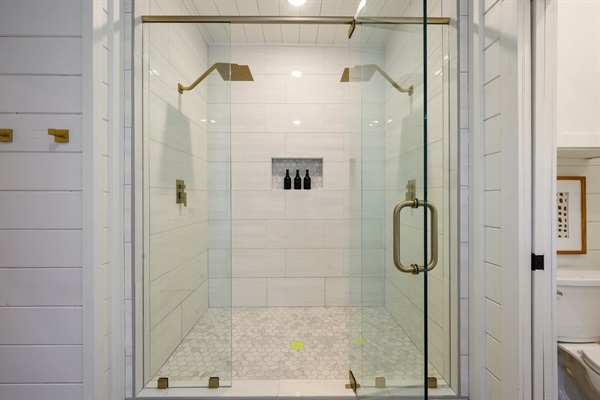A spacious glass walk-in shower with dual rainfall showerheads offers a luxurious experience.