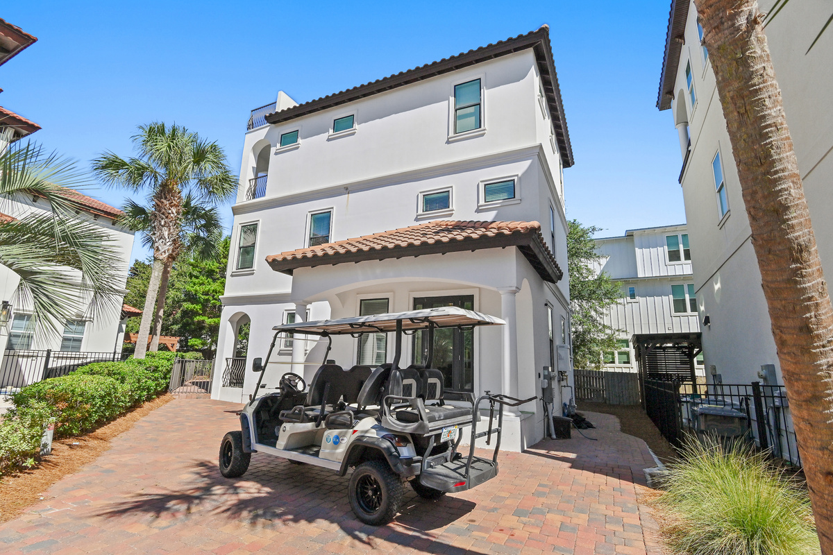 Bright and inviting exterior with a spacious brick courtyard and golf cart.