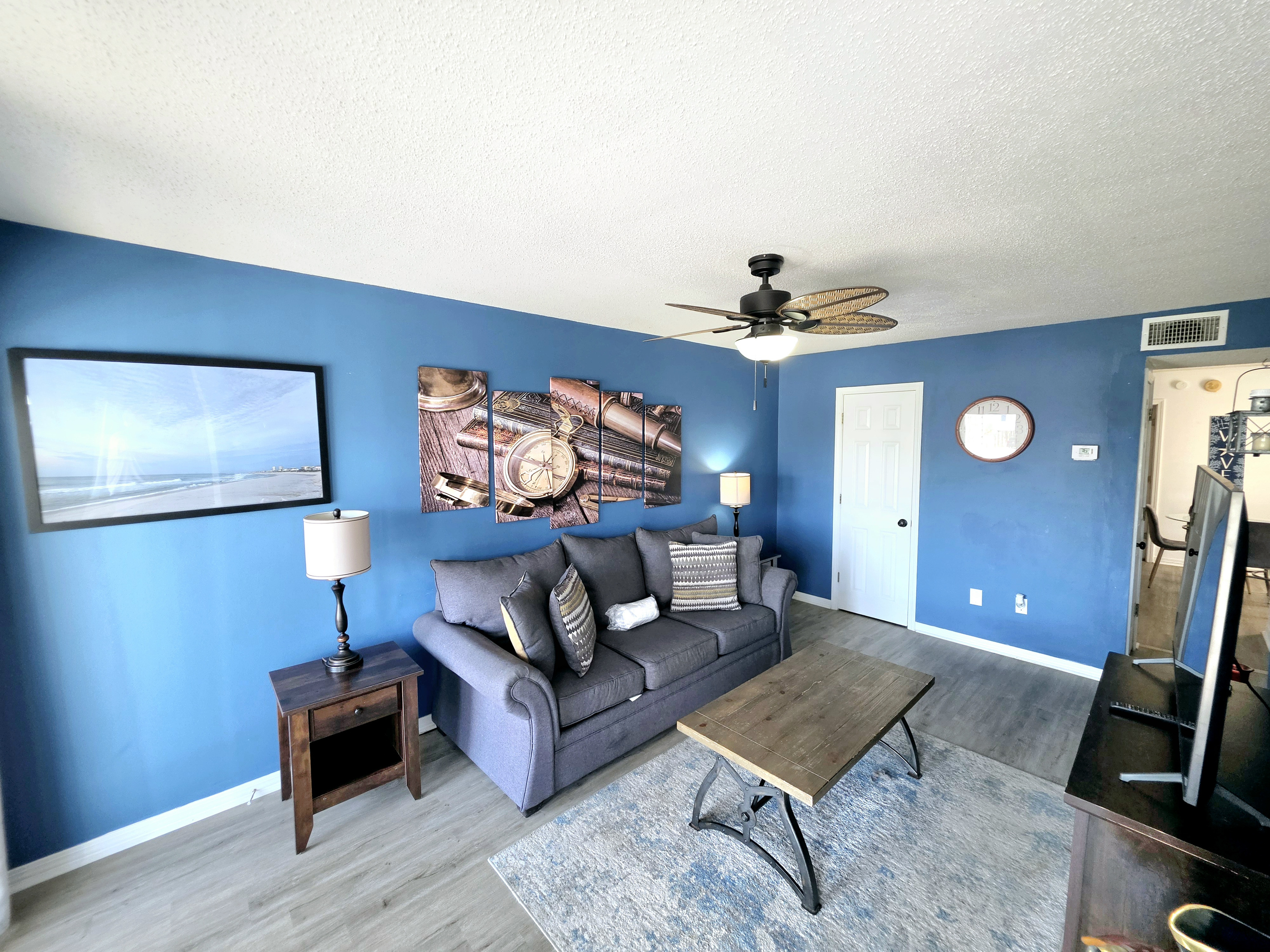 Nest side – Living room with sofa, coffee table and nautical wall art