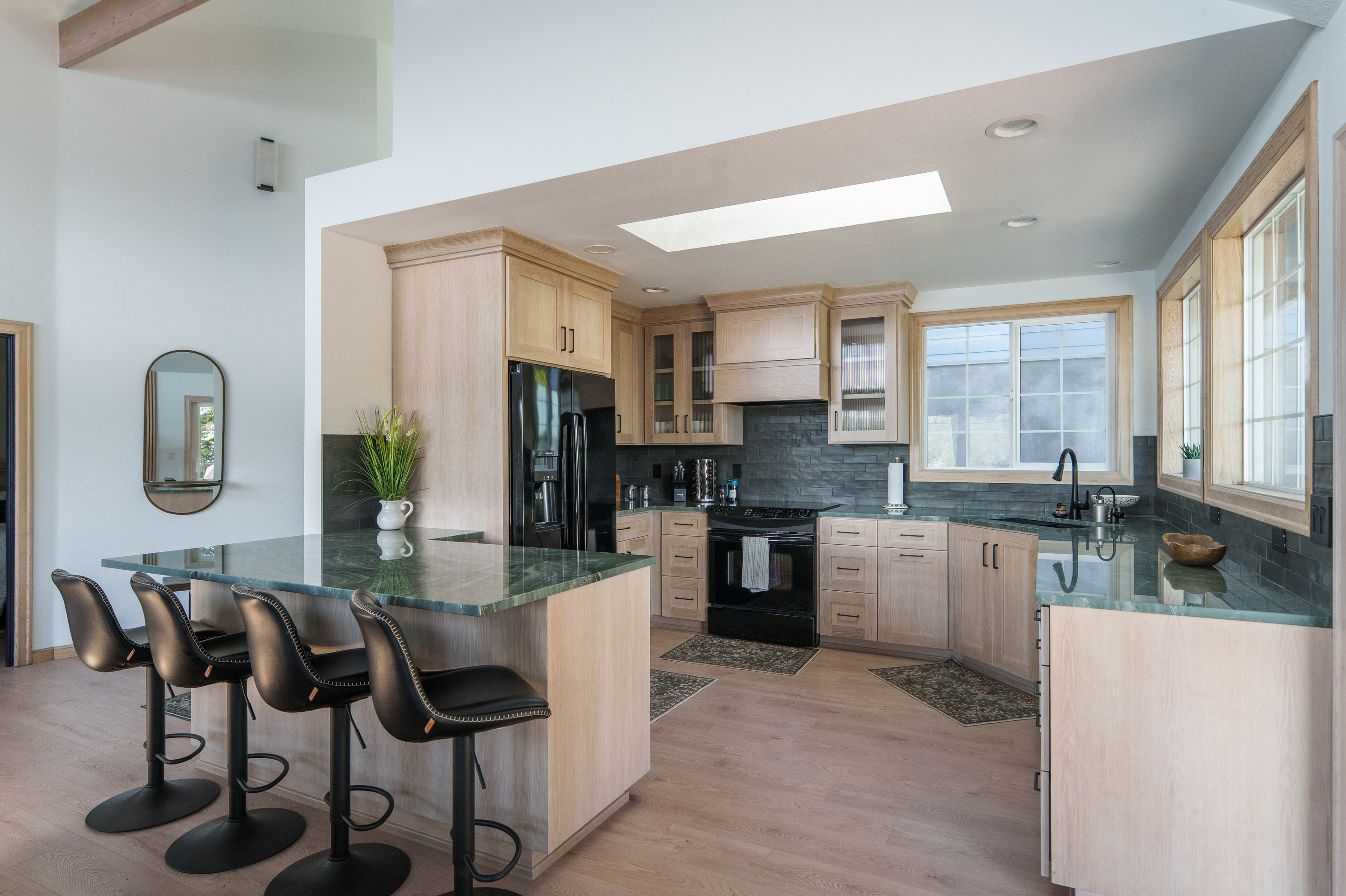 Fully equipped kitchen with modern appliances, generous counter space, and large windows that fill the room with natural light. Coffee station includes Keurig k-cup pods and traditional ground coffee maker
