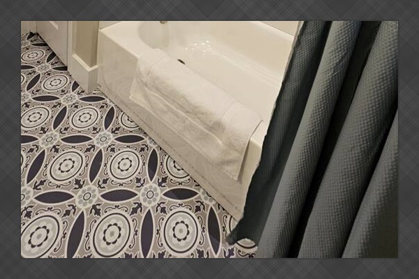 This bathroom features a clean and classic tub-shower combo with crisp white subway tile and built-in shelving, paired with a modern curved shower rod and a soft blue curtain. The patterned tile floor adds a bold, stylish contrast to the neutral tones.