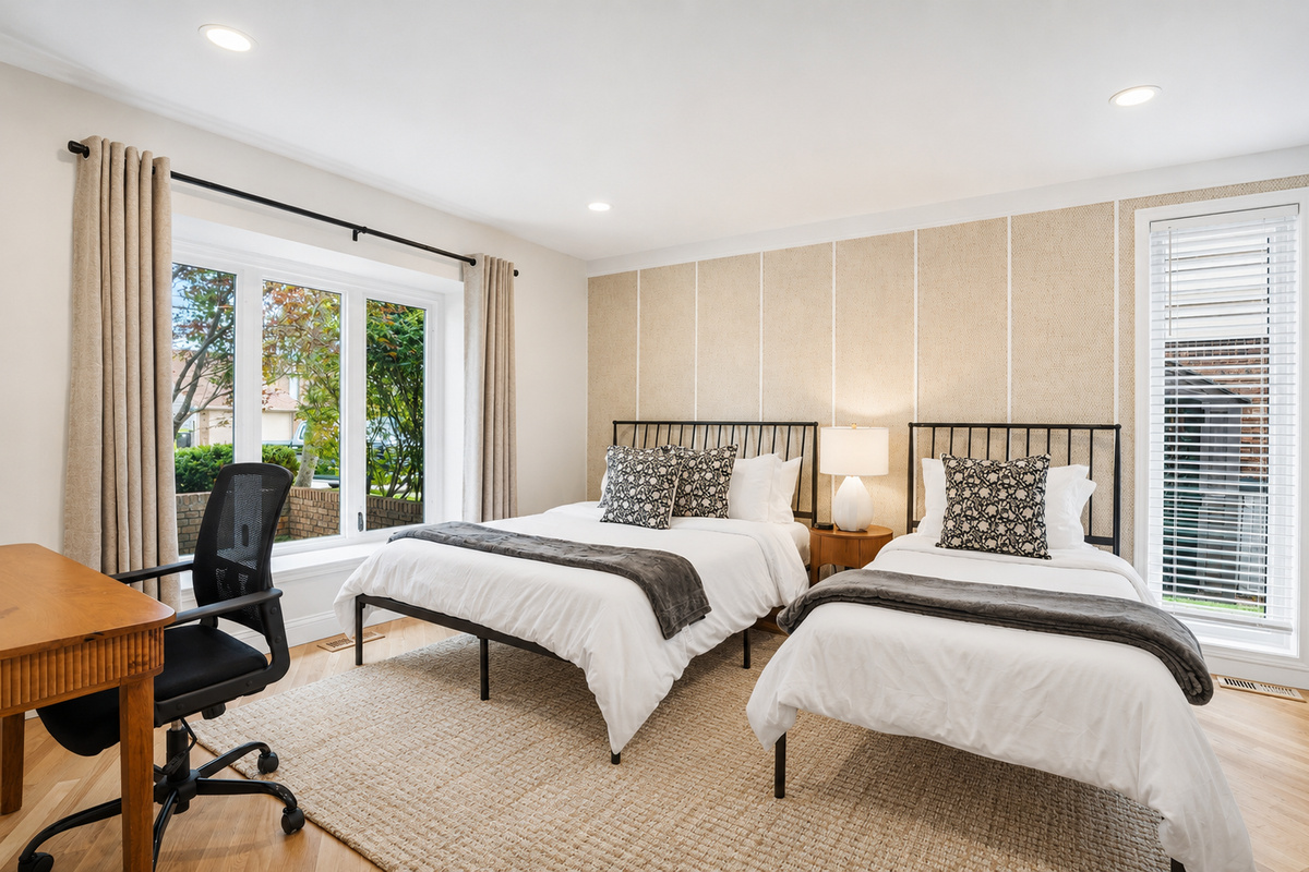 Bright, spacious bedroom with two comfortable beds, modern neutral décor, and large windows bringing in natural light. Clean, relaxing space perfect for families or group stays.
