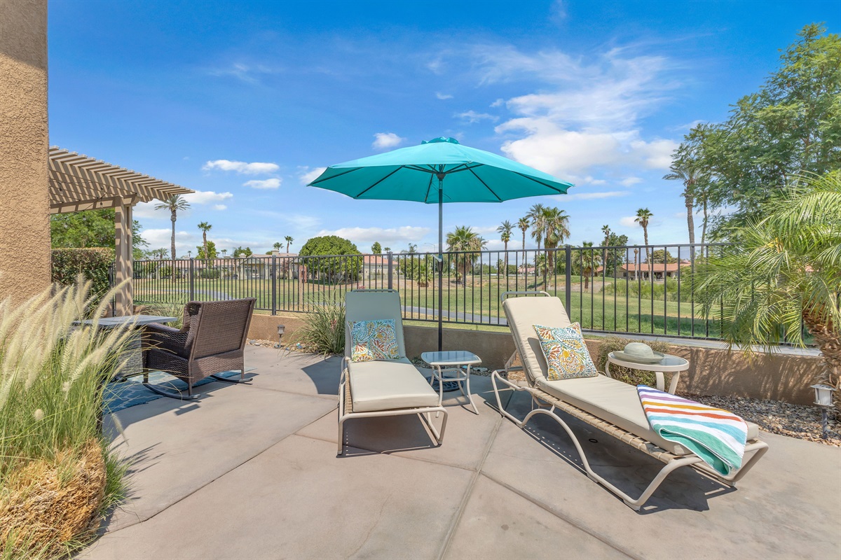 Sunny patio with loungers, umbrella & golf views