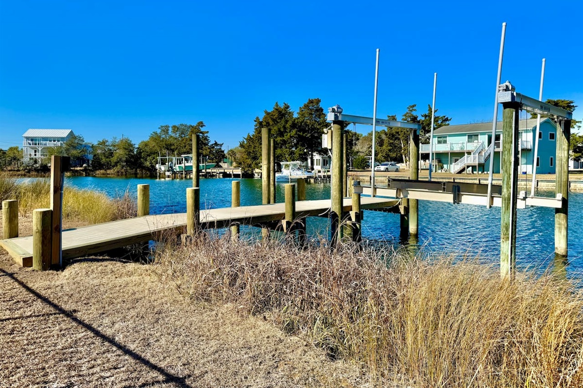 Private backyard dock with boat lift and fillet table, fenced-in backyard, fire pit with Adirondack chairs, hammocks, propane grill, picnic table, outdoor shower, expansive waterfront back deck, neighborhood boat ramp and dock