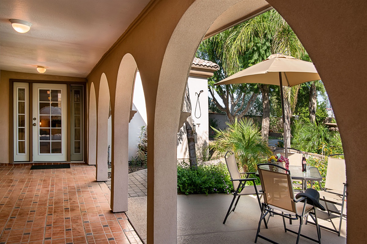 Lounge beneath graceful arches with views of the sparkling pool and blooming desert flowers in this serene outdoor living space.