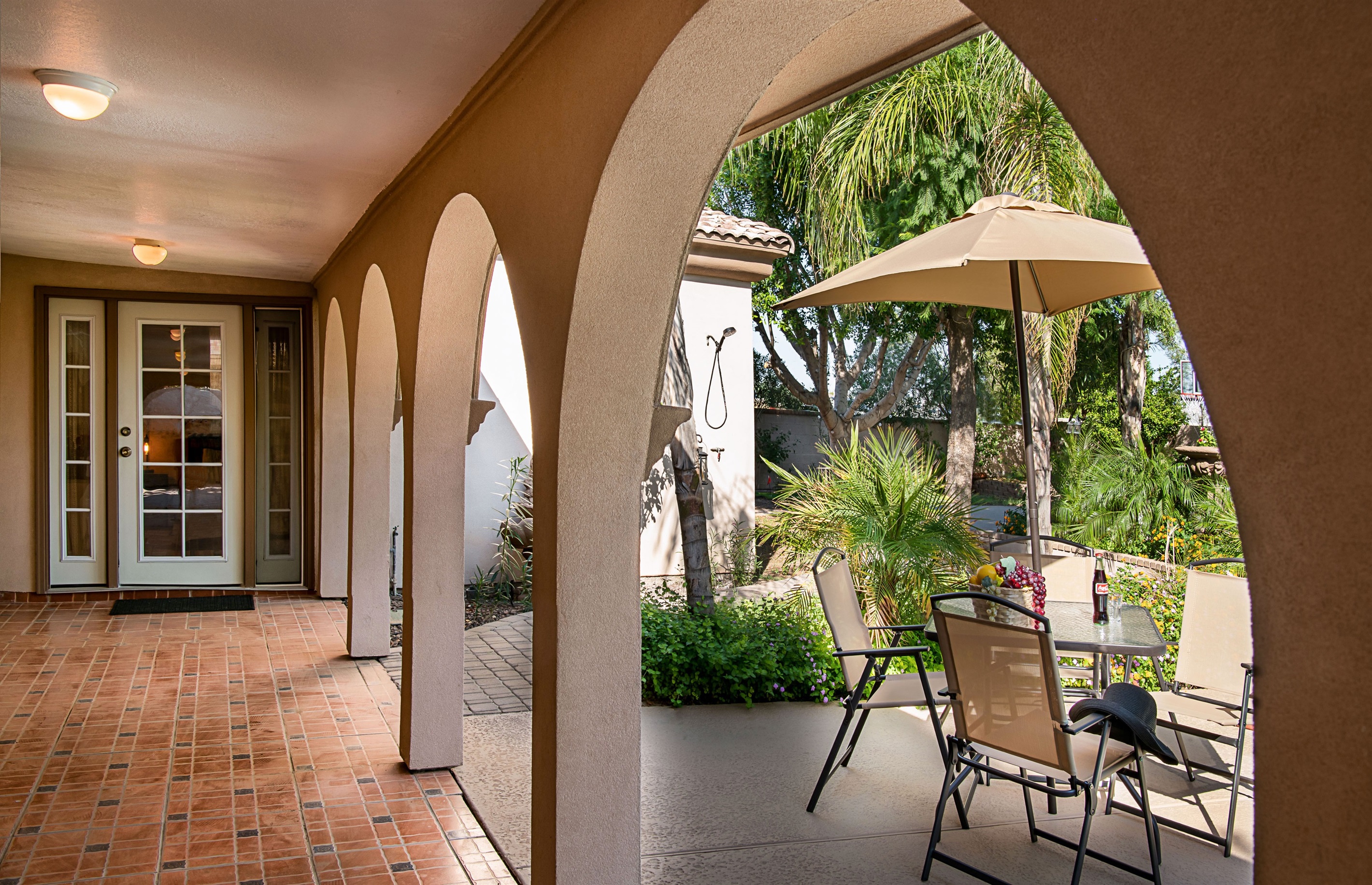 Lounge beneath graceful arches with views of the sparkling pool and blooming desert flowers in this serene outdoor living space.