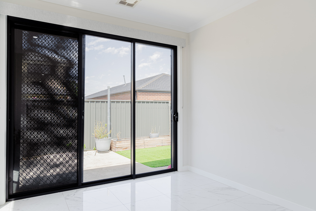 Sliding glass doors connect the room to the backyard, with screen access, gloss tiled floors and natural light throughout the space.