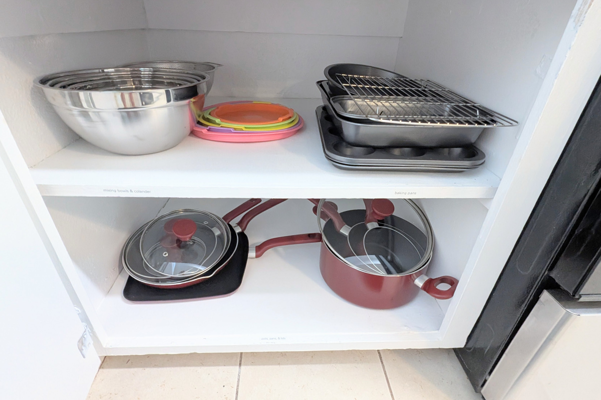 The kitchen is stocked with mixing bowls with lids, baking sheets and pans, and a full set of pots and pans with matching lids.