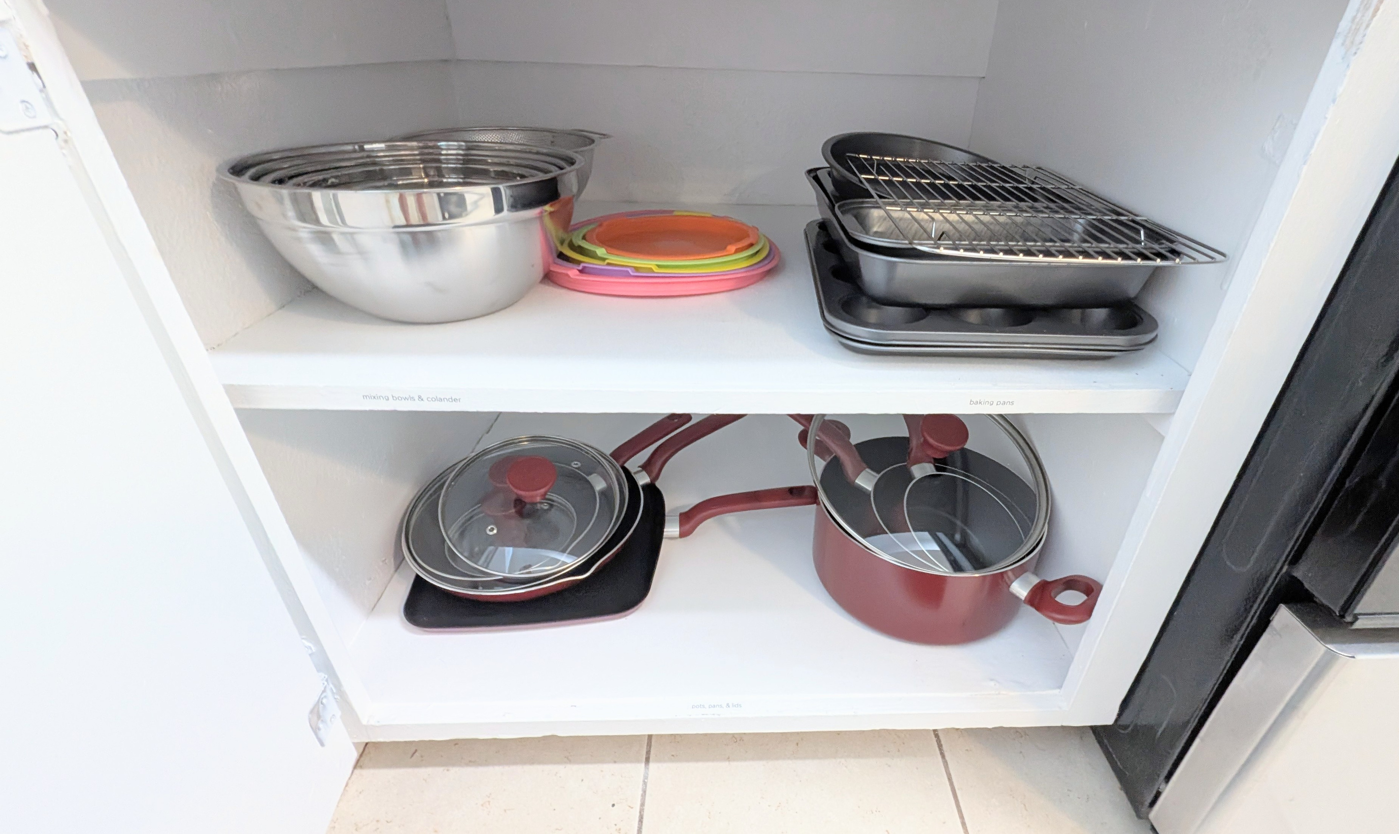 The kitchen is stocked with mixing bowls with lids, baking sheets and pans, and a full set of pots and pans with matching lids.