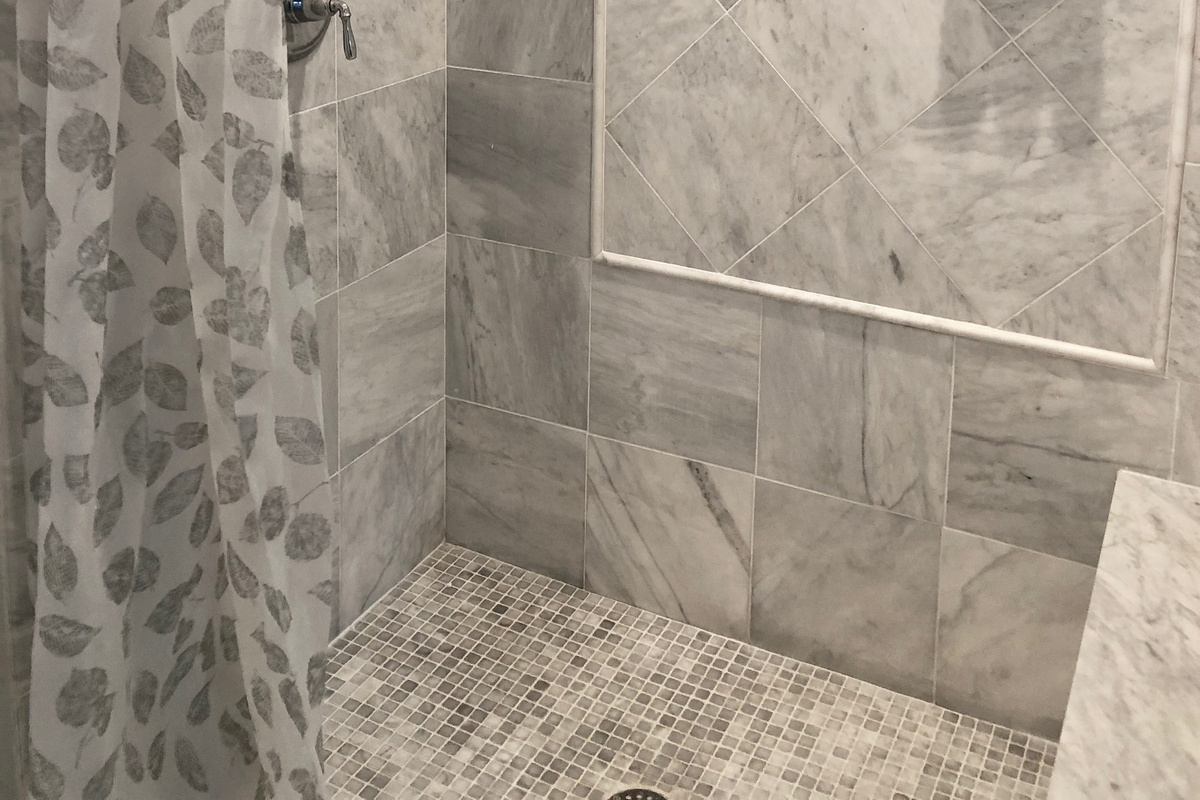 The ensuite bath features a sleek walk-in shower, marble tile, and spa-style fixtures—your own private escape just steps from the bed.