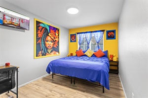 Bedroom 2 features warmth complemented by cheerful, vibrant artworks